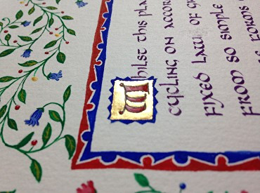 A side on view of a decorated piece of text,  it's an extract from Darwin's On The Origin of Species that begins "whilst this planet", but the angle makes the whole text hard to read. The inital letter W is written in a historic curved style with broad strokes coloured in red, and on a gold leaf background that gleams. Twisting vines wander around the border of the text. 